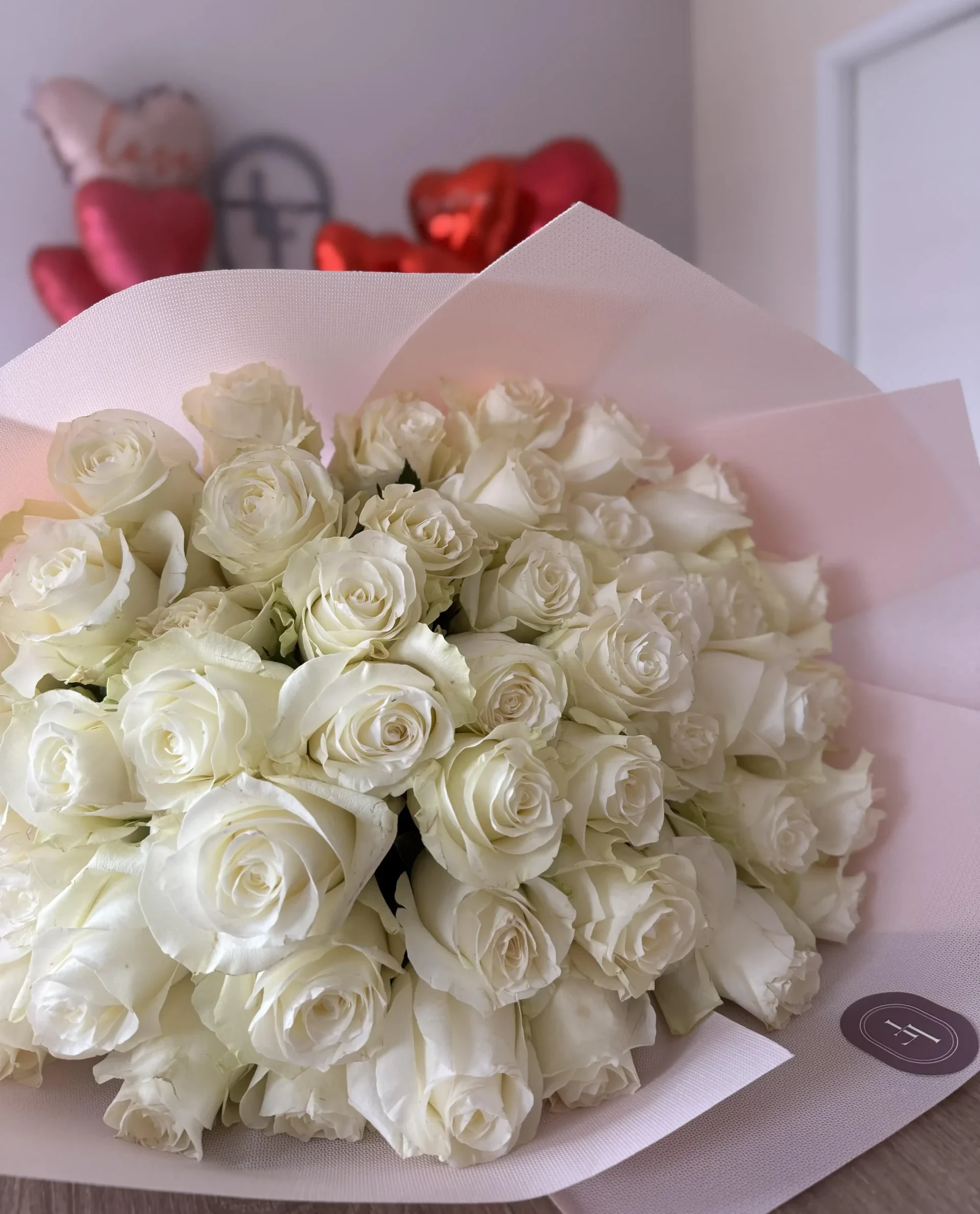 Elegant White O’Hara bouquet wrapped in soft pink paper, composed of long-stemmed ivory roses with a romantic ambiance
