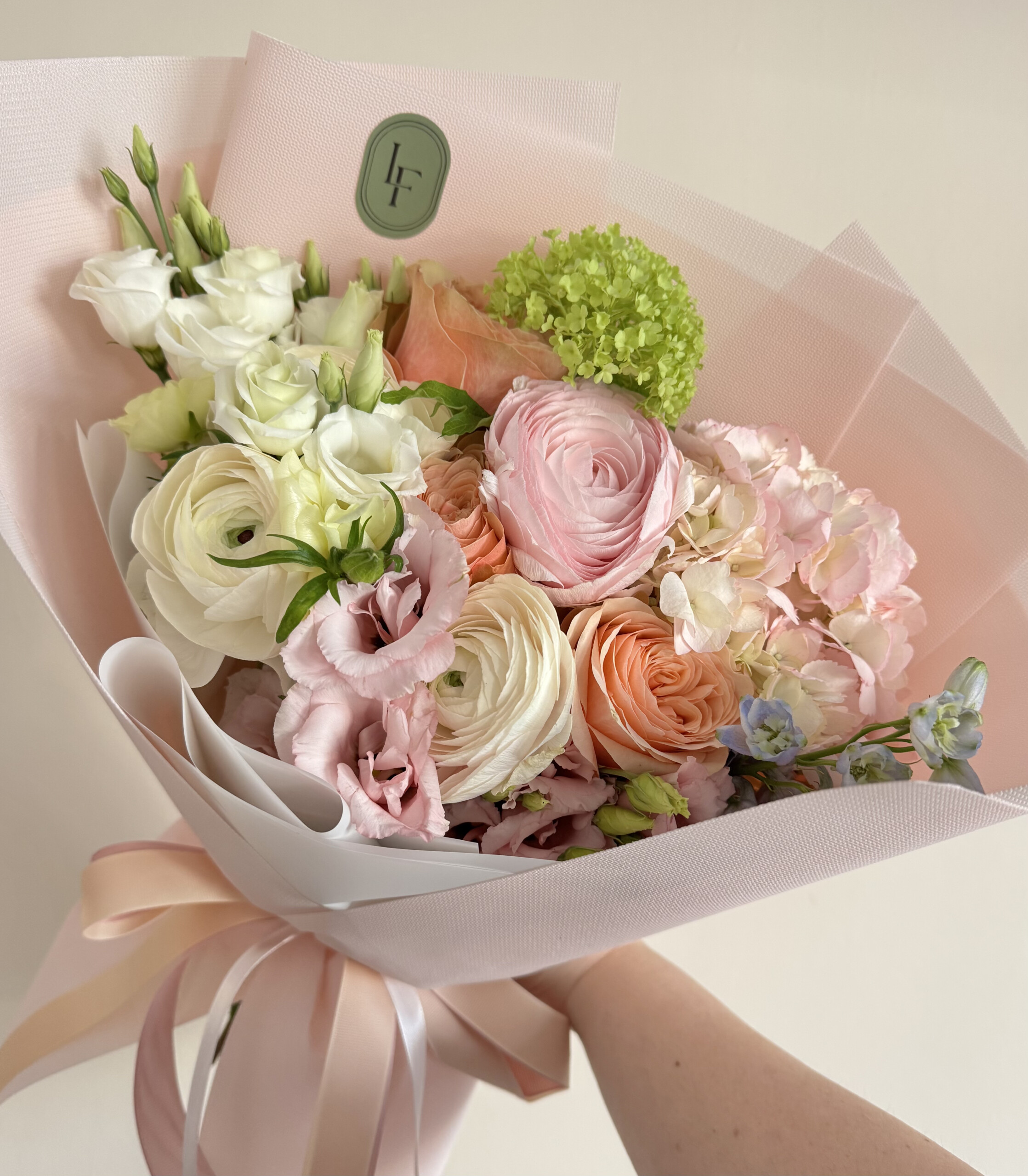 Pastelowy bukiet z róż, jaskrów, eustomy i hortensji w romantycznym stylu, delikatnie ułożony w elegancką kompozycję przez LuLaFleur.
