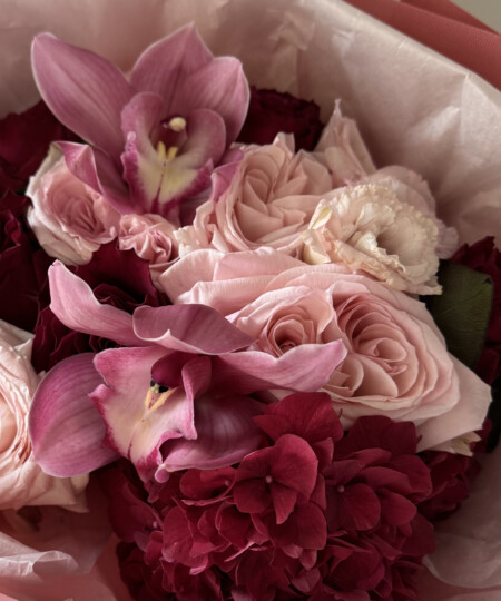 Zbliżenie na różowe storczyki cymbidium i jasnoróżowe róże ogrodowe w bukiecie Wine Passion